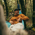 Man wearing Montane Featherlite laughing sat in hammock